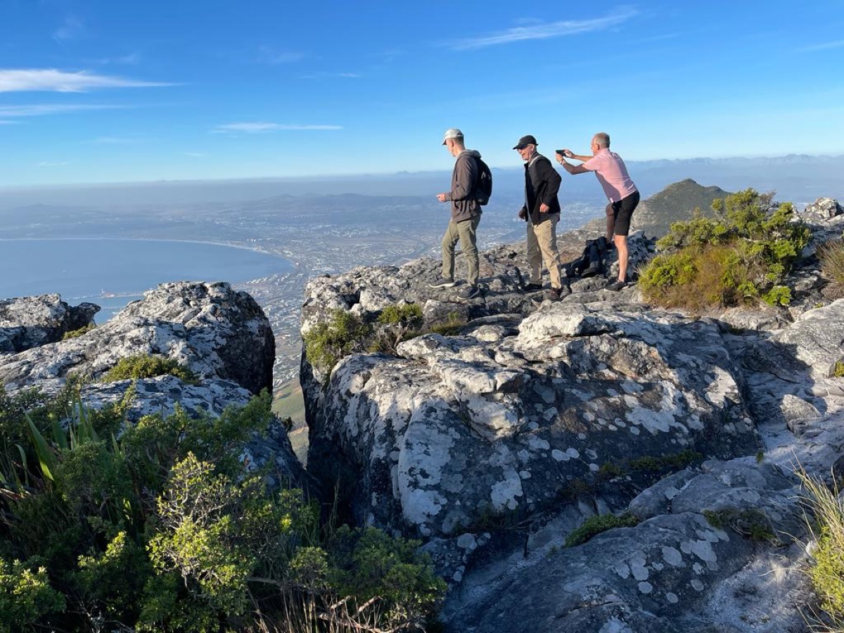 Hikers on rocky lookout above a city and coastline